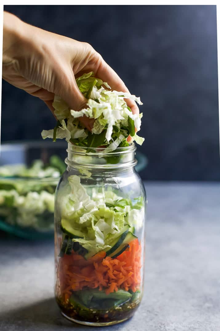 Shredded lettuce being added to a mason jar salad