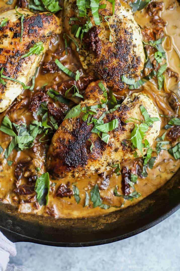 Close up view of Creamy sun dried tomato chicken with fresh herbs in a skillet