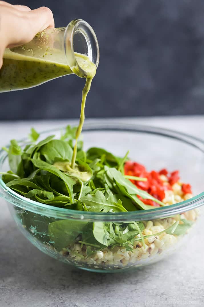 Jalapeno Dressing being poured over Grilled Corn Salad ingredients in a bowl