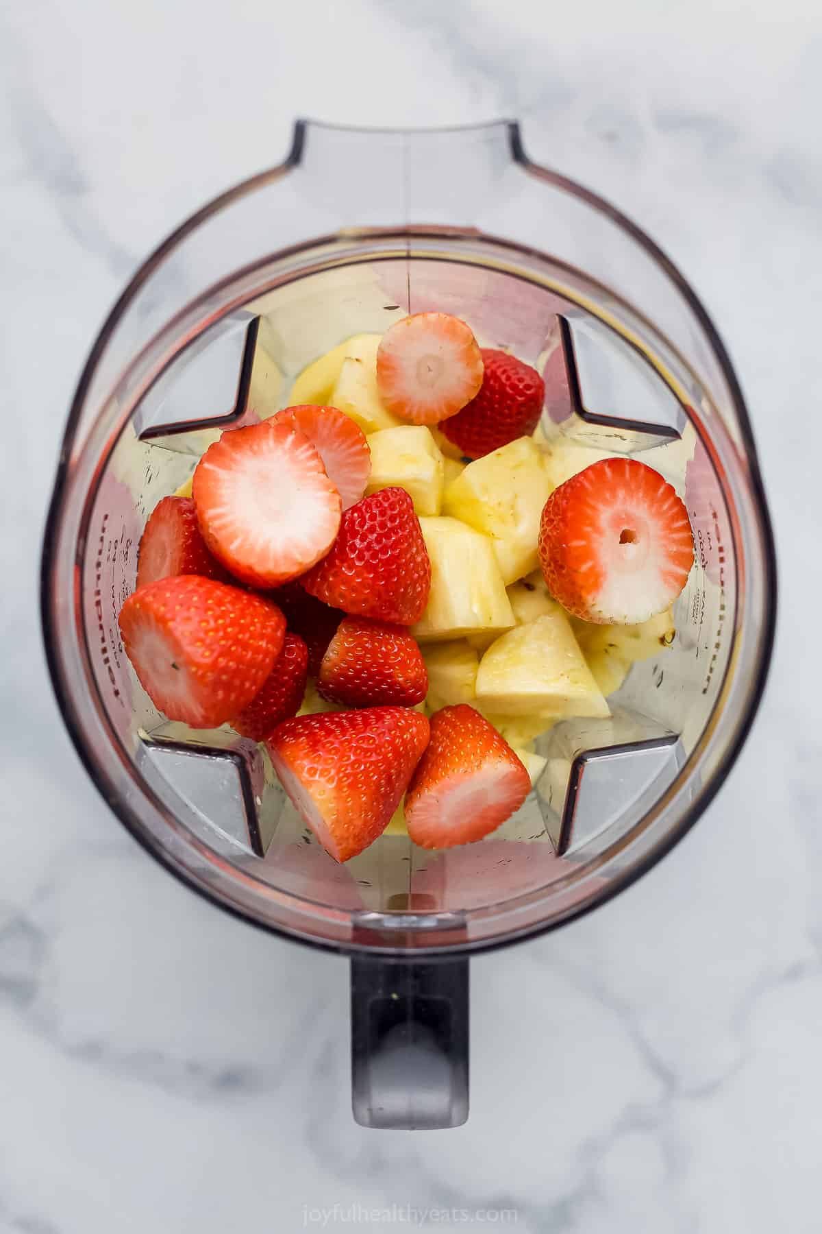 Chunks of strawberry and pineapple in a blender
