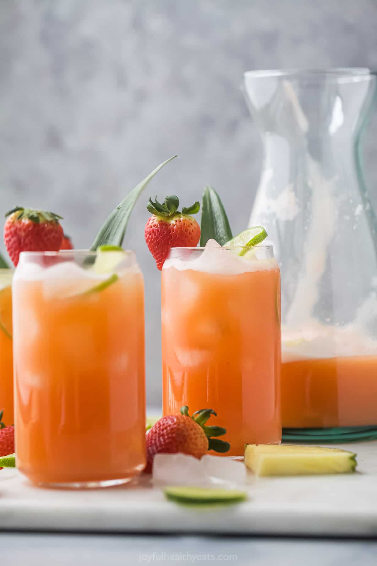 Two glasses of agua fresca in front of a pitcher