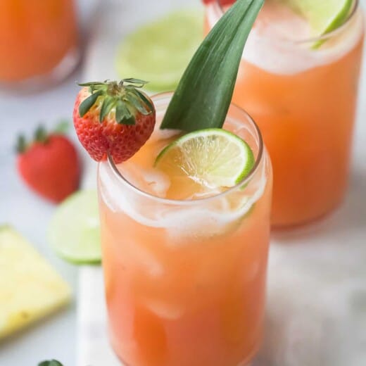 A glass of strawberry agua fresca garnished with a strawberry and lime slice