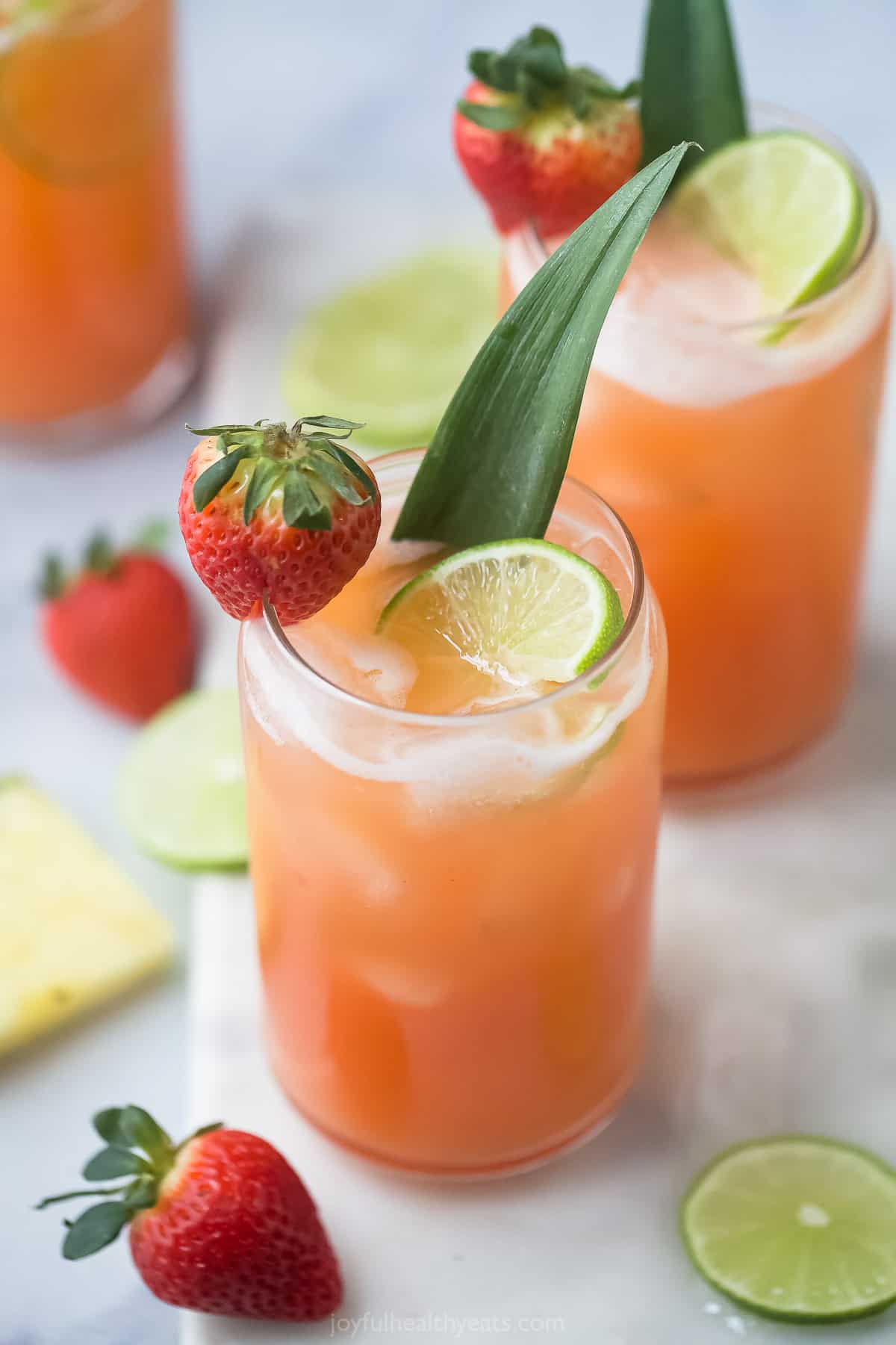 A glass of strawberry agua fresca garnished with a strawberry and lime slice