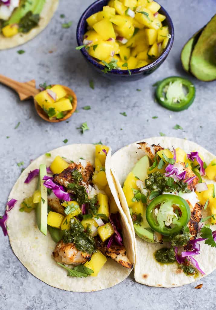 Vue de dessus de deux TACOS DE POISSON GRILLÉ garnis de SALSA à la MANGUE fraîche, d'avocat et de Chimichurri