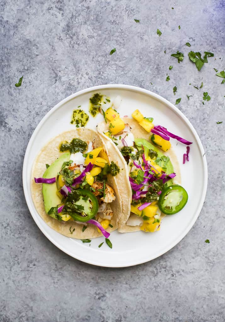 Vue de dessus des TACOS DE POISSON GRILLÉS avec SALSA de MANGUE fraîche, Avocat et Chimichurri sur une assiette