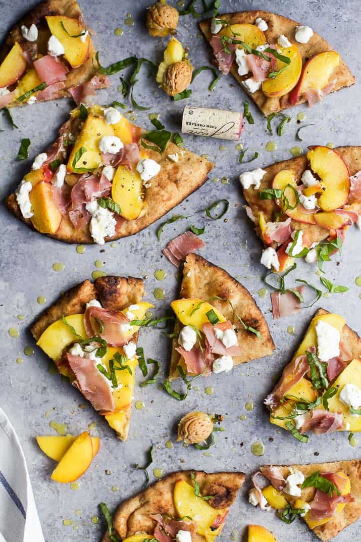 Top view of wedges of Grilled Flatbread Pizza topped with Peaches, Prosciutto, Goat Cheese, and fresh Basil