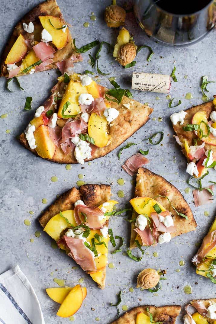 Top view of wedges of Grilled Flatbread Pizza topped with Peaches, Prosciutto, Goat Cheese, and fresh Basil