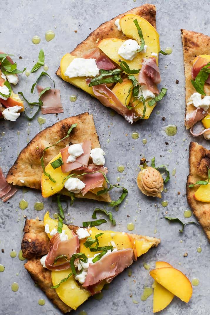 Top view of wedges of Grilled Flatbread Pizza topped with Peaches, Prosciutto, Goat Cheese, and fresh Basil