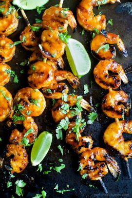 Honey sriracha grilled shrimp garnished with chopped parsley and fresh lime slices