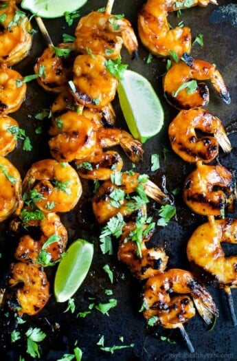 Honey sriracha grilled shrimp garnished with chopped parsley and fresh lime slices