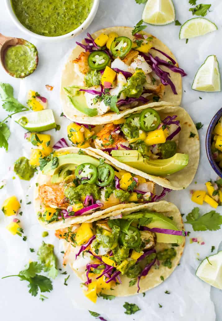 Overhead view of fish tacos with mango salsa, avocado, red cabbage and cilantro