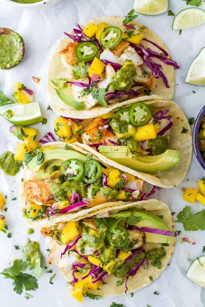 Overhead view of fish tacos with mango salsa and garnishes