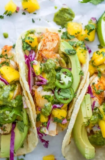 Close-up overhead view of fish tacos with mango salsa and garnishes