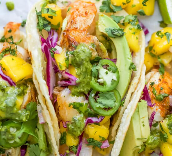 Close-up overhead view of fish tacos with mango salsa and garnishes