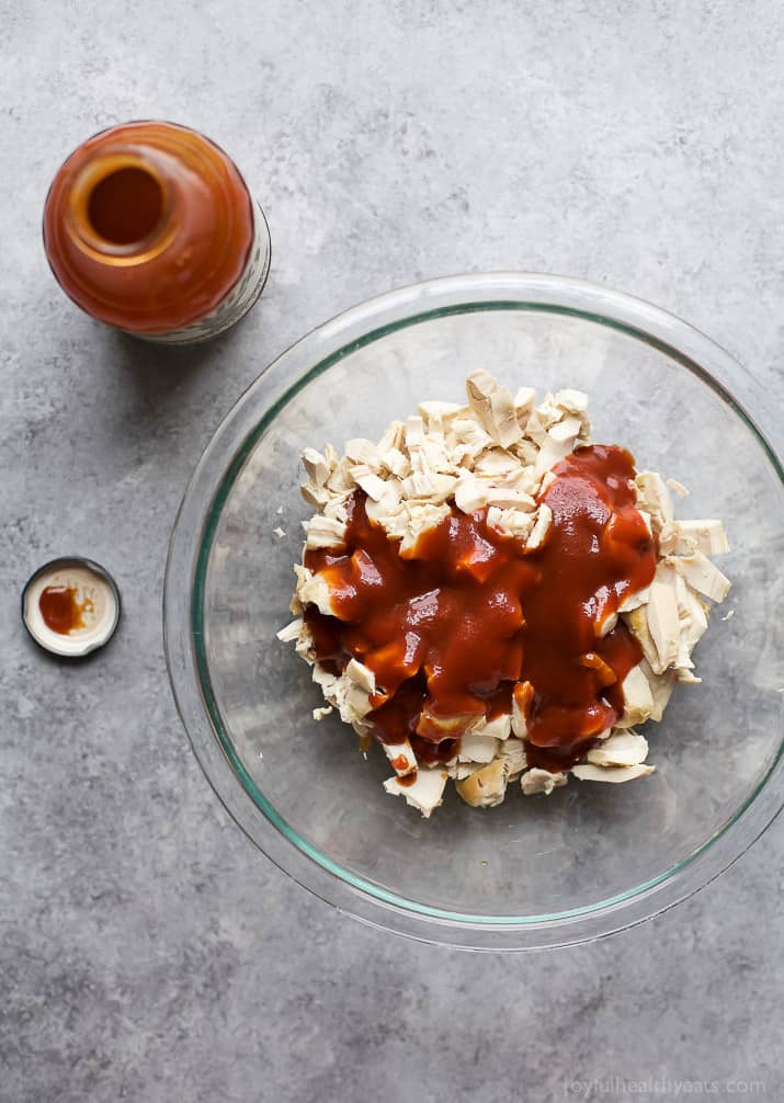 Chopped cooked chicken and BBQ sauce in a mixing bowl