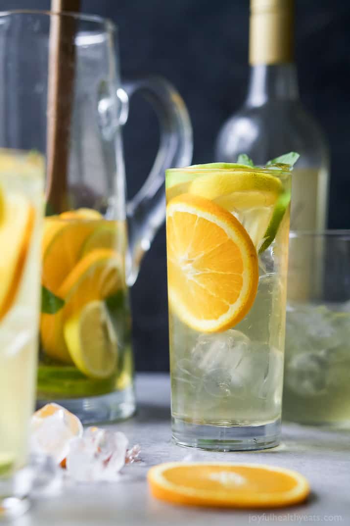 A tall glass of Citrus White Wine Sangria with sliced citrus fruit and fresh mint