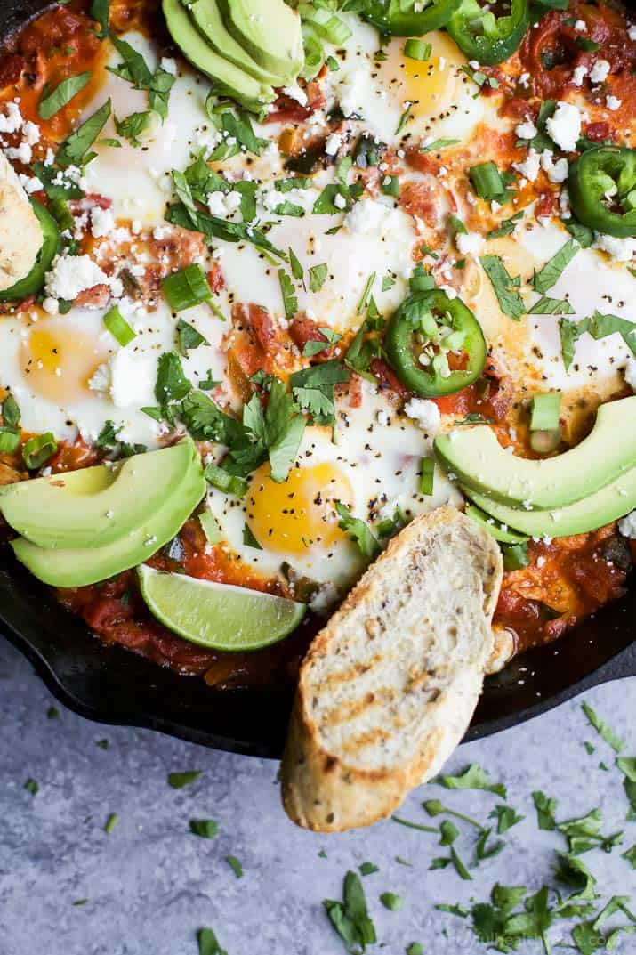 A close-up shot of shakshouka in a pan with two slices of toasted bread