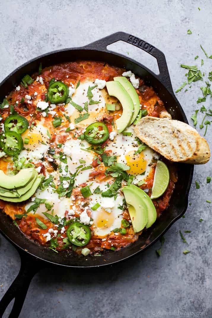 A bird's-eye view of homemade shakshuka in a pan with chopped herbs on top