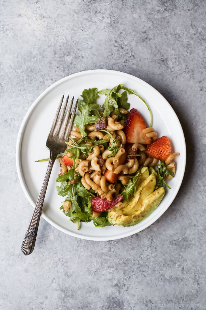 Easy Strawberry Avocado Pasta Salad tossed with fresh arugula, bacon, and a balsamic vinaigrette. The perfect pasta salad for those summer nights! | #ad | gluten free recipes