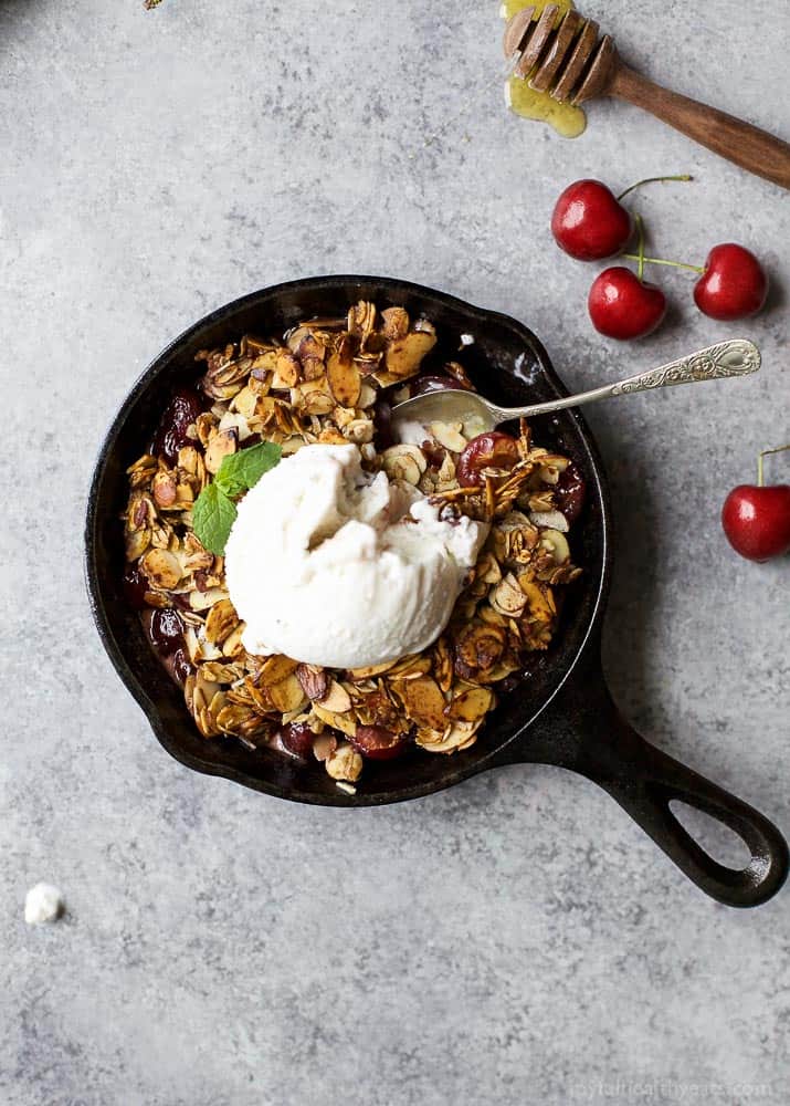 Top view of Cherry Crisp in a cast-iron pan with a scoop of vanilla ice cream