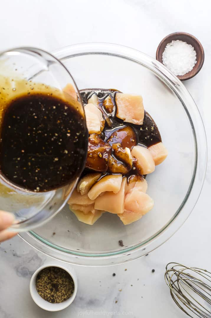 pouring balsamic marinade over cubed chicken