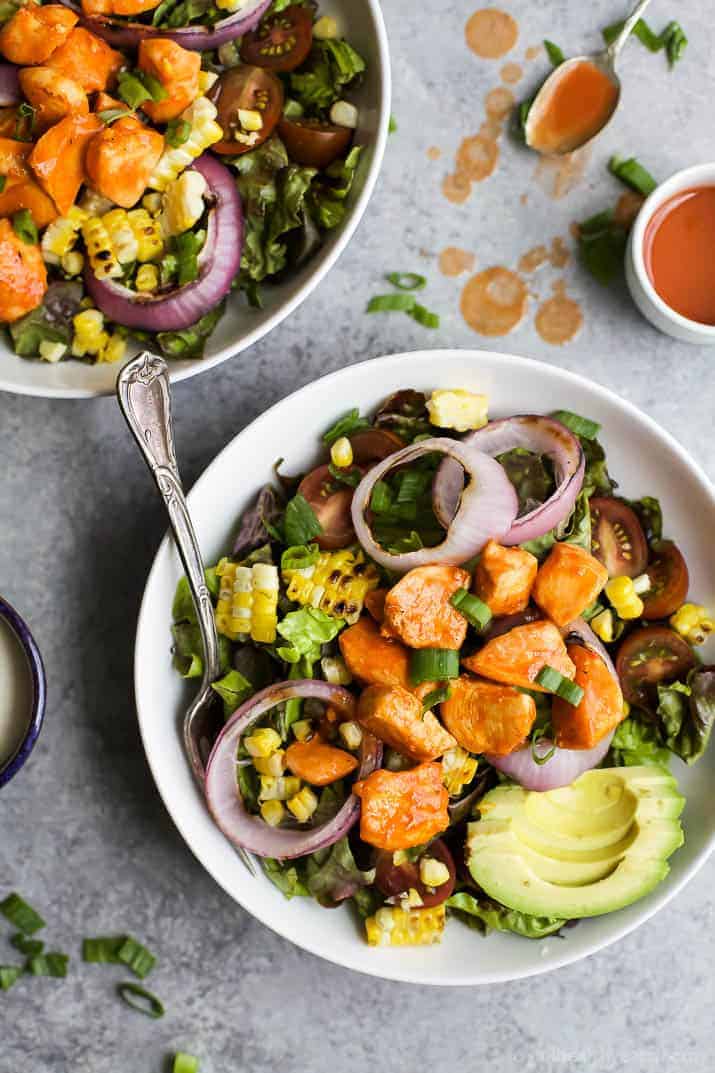 Top view of Grilled Buffalo Chicken Salad in a bowl with corn, red onion and sliced avocado