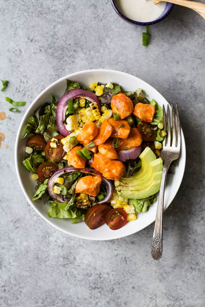 Top view of Grilled Buffalo Chicken Salad in a bowl with corn, red onion and sliced avocado