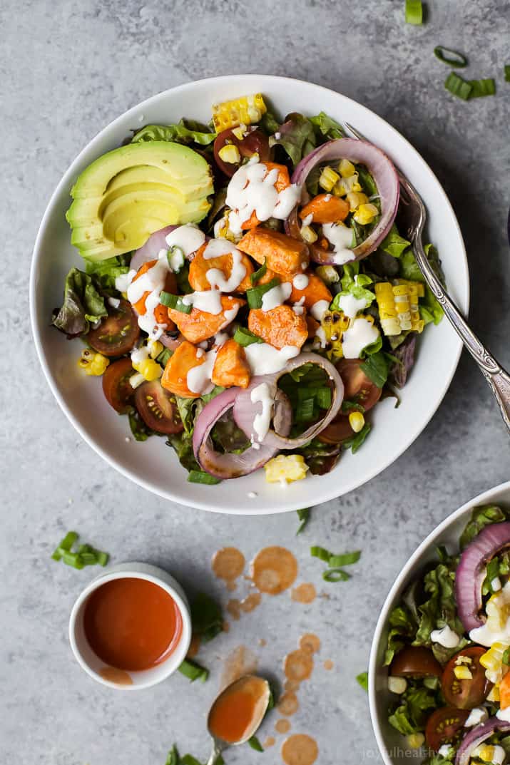 Top view of Grilled Buffalo Chicken Salad in a bowl with corn, red onion and sliced avocado