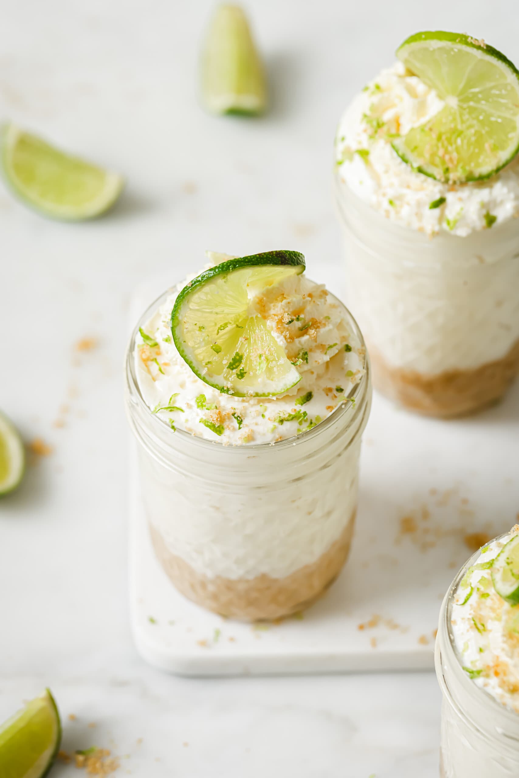 Angled p،to of key lime cheesecake in a jar with whipped cream on top. 