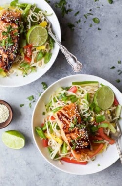 Two bowls of Easy Teriyaki Salmon served on a bed of Asian Noodles made with brown rice noodles, fresh veggies and a homemade Asian Sesame Dressing! | gluten free recipes