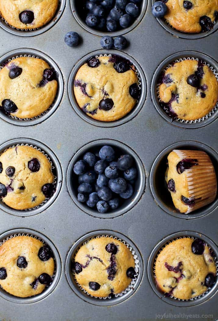 An overhead shot of a pan full of baked muffins with fresh berries scattered about