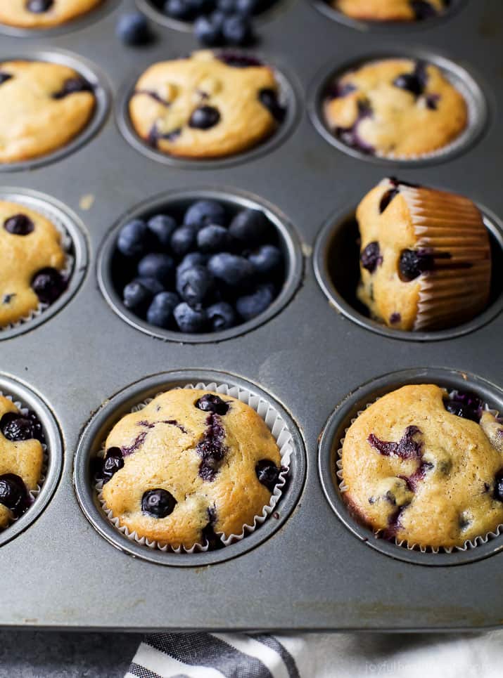 Blueberry muffins inside of a lined cupcake tin with some of the divots filled with blueberries