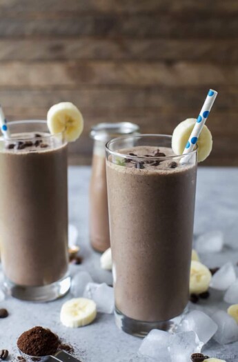 Two glasses full of Cafe Mocha Smoothie served with banana wedges and a straw