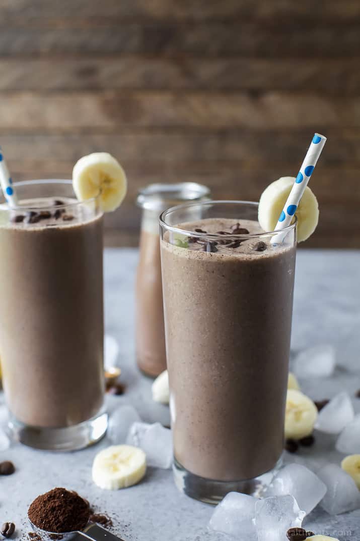 mocha-colored smoothie in a glass with choclate chips and banana garnish with a straw