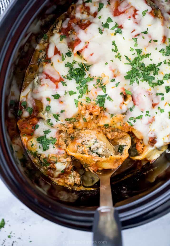 a spoon in a crock pot filled with stuffed shells