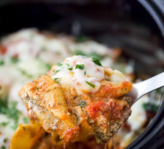 a spoon holding stuffed shells filled with ricotta and spinach