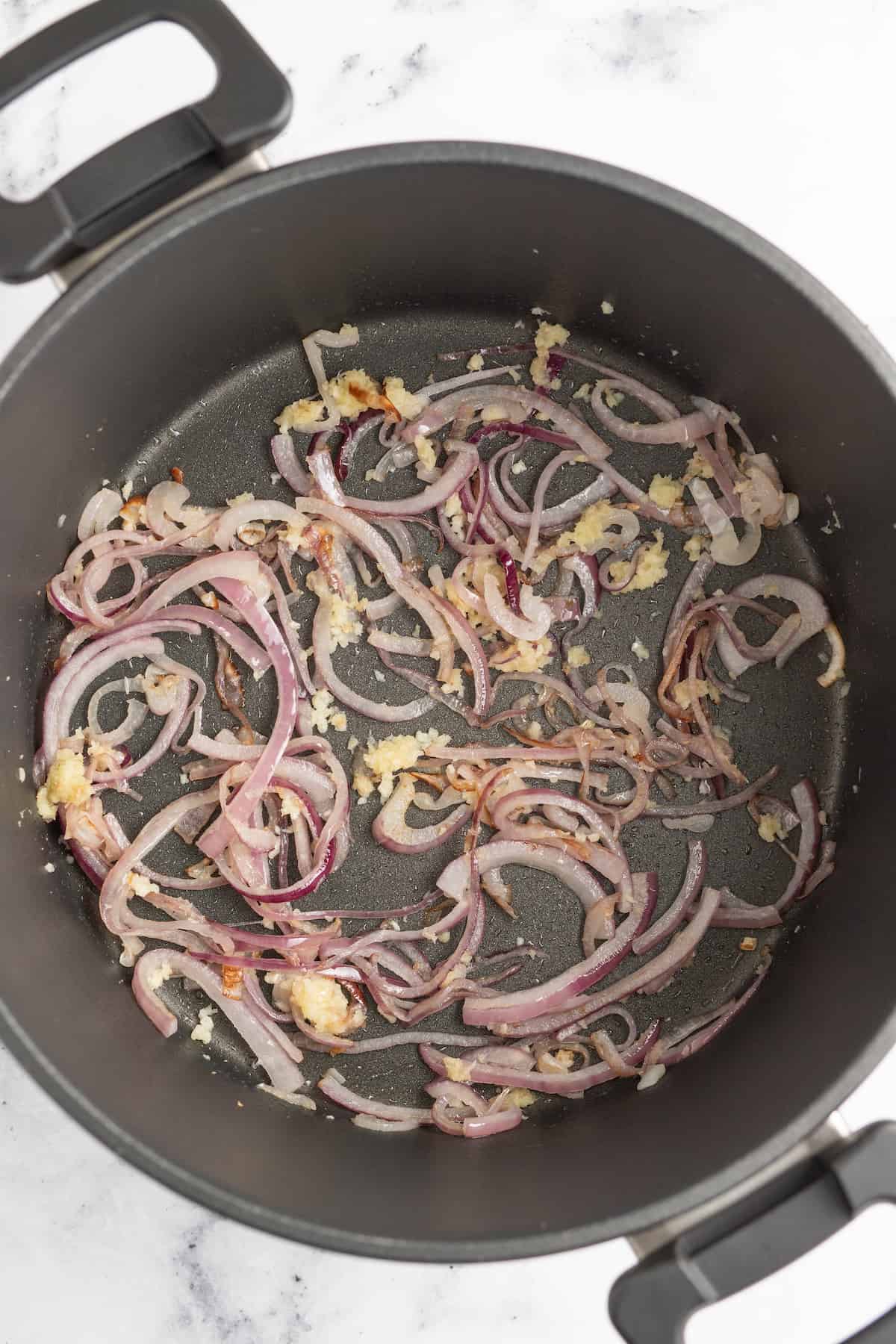 a large pot with sliced cooked onions and garlic