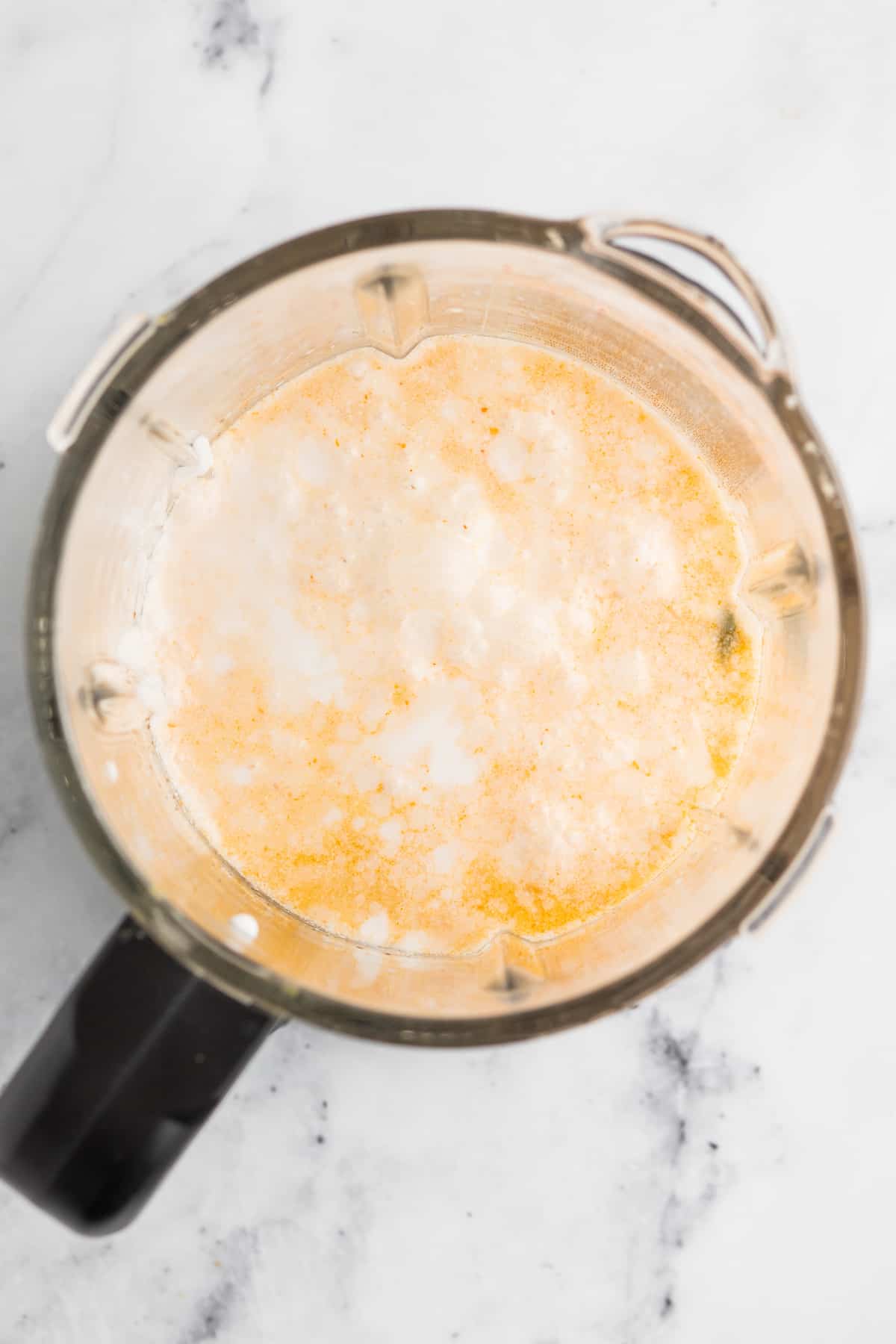 a blender with a light orange cream mixture