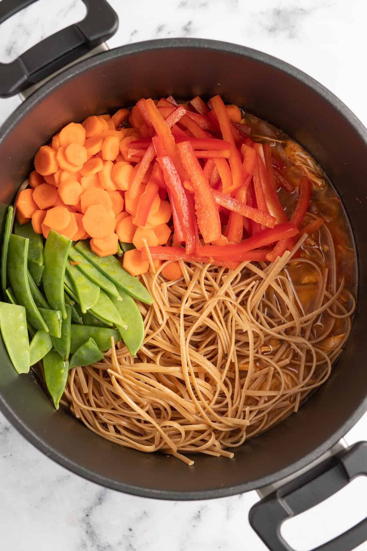 a large pot with an assortment of vegetables and noodles