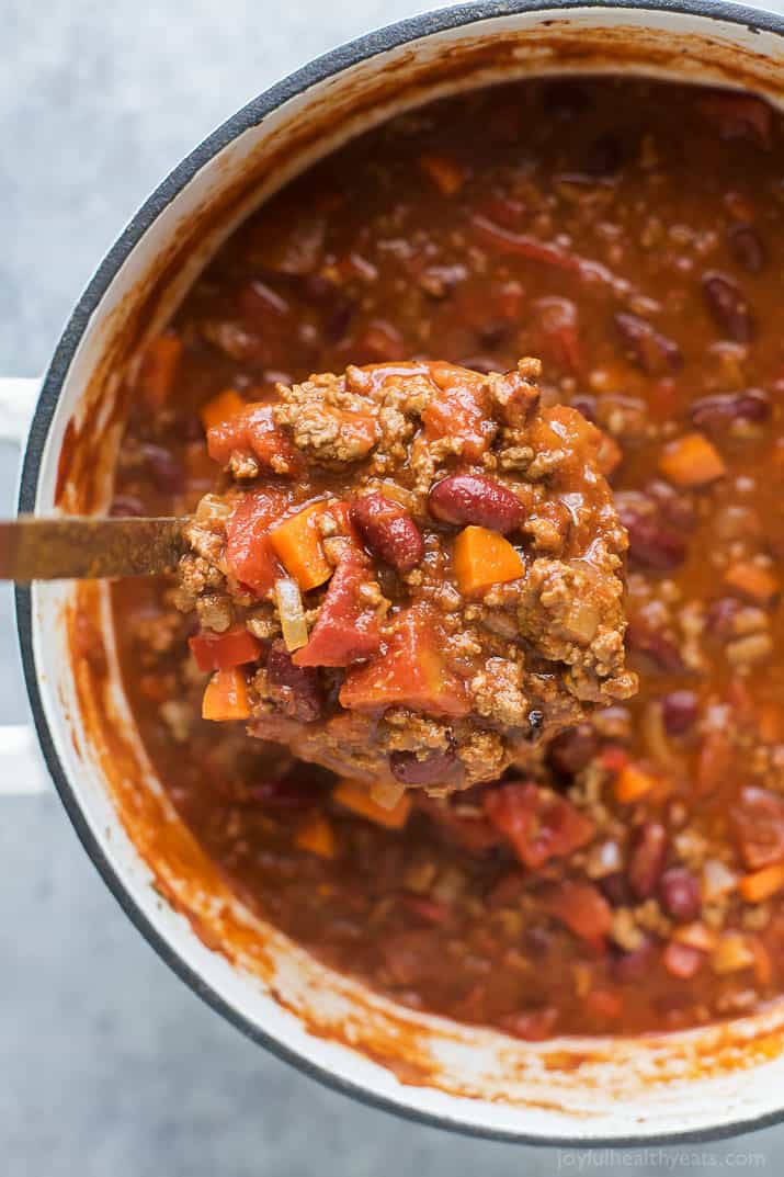 Ladle scooping beef chili from a dutch oven
