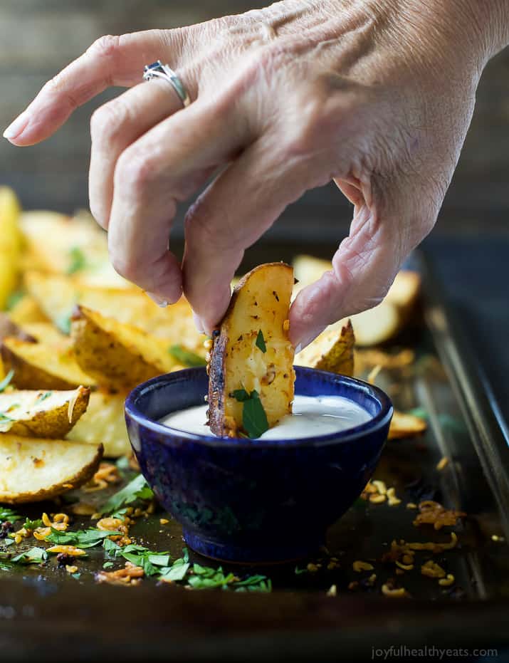 A Garlic Parmesan seasoned Potato Wedge being dipped into creamy sauce