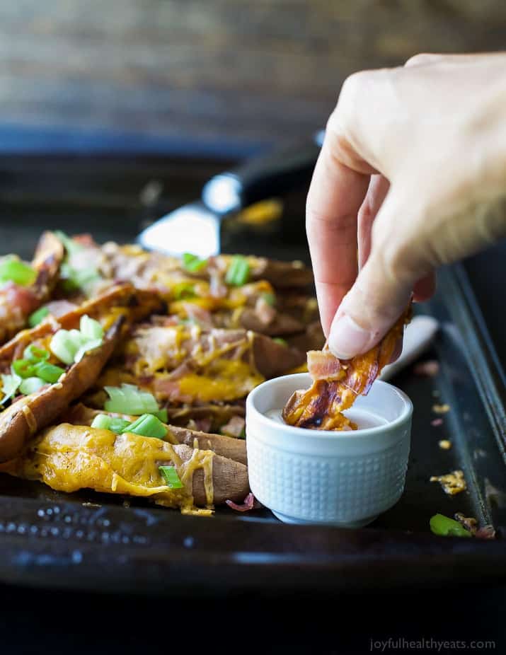 Loaded Sweet Potato Wedges on a baking sheet with dipping sauce