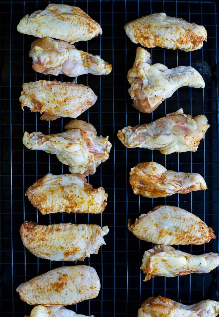 Chicken wings lined up on a wire rack over a baking sheet