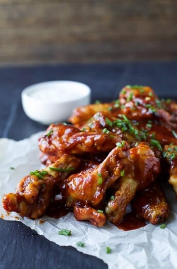 A pile of honey BBQ wings on top of a sheet of parchment paper