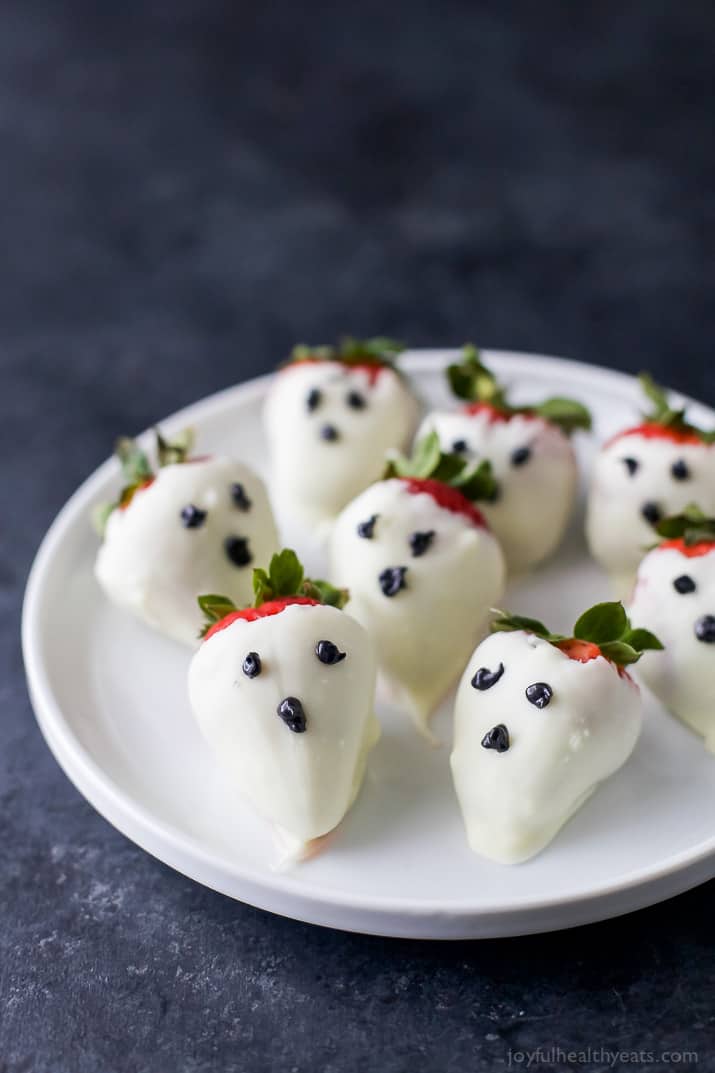 White chocolate dipped strawberries decorated like ghosts on a plate