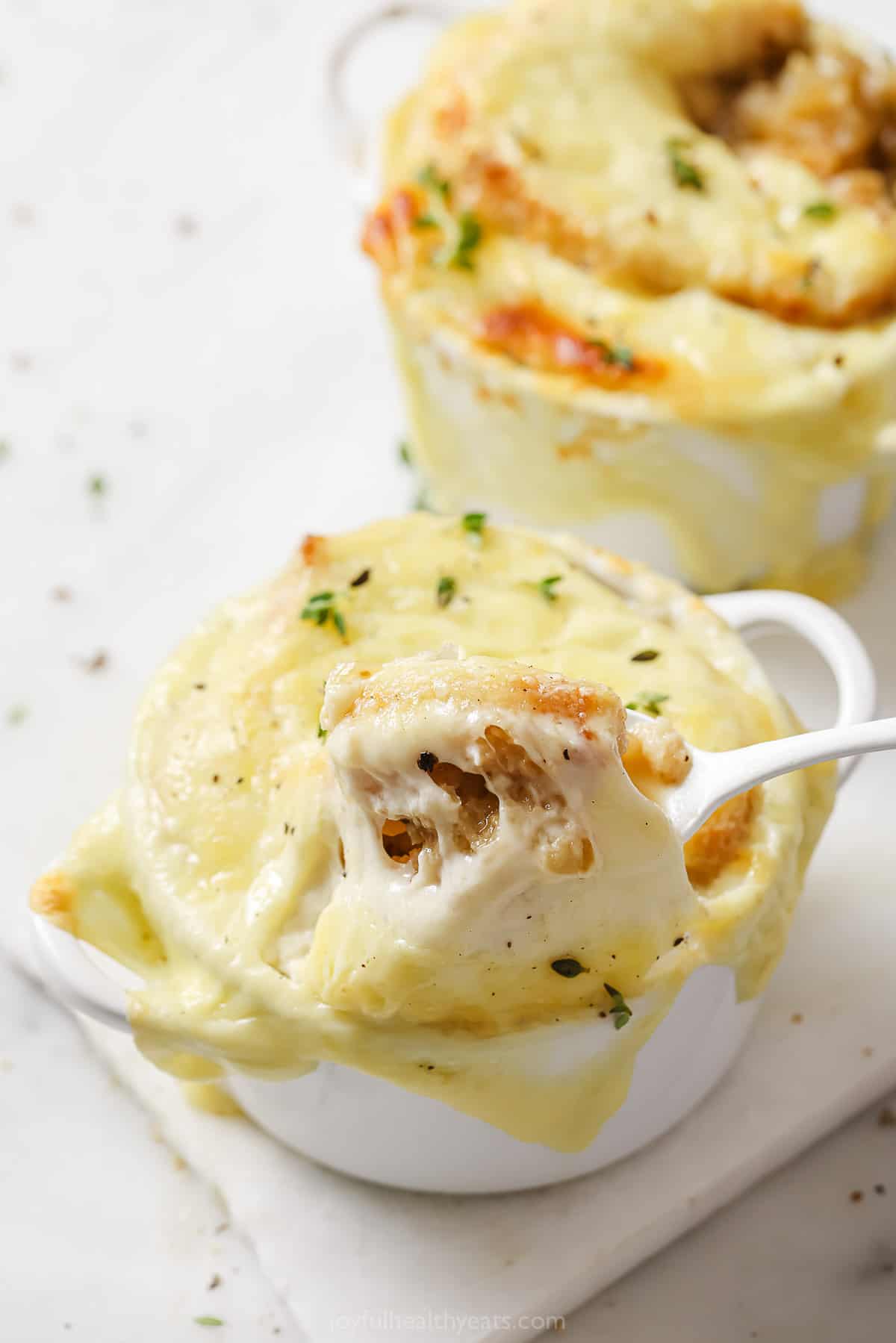 Spoonful of onion soup with a cheese pull. 