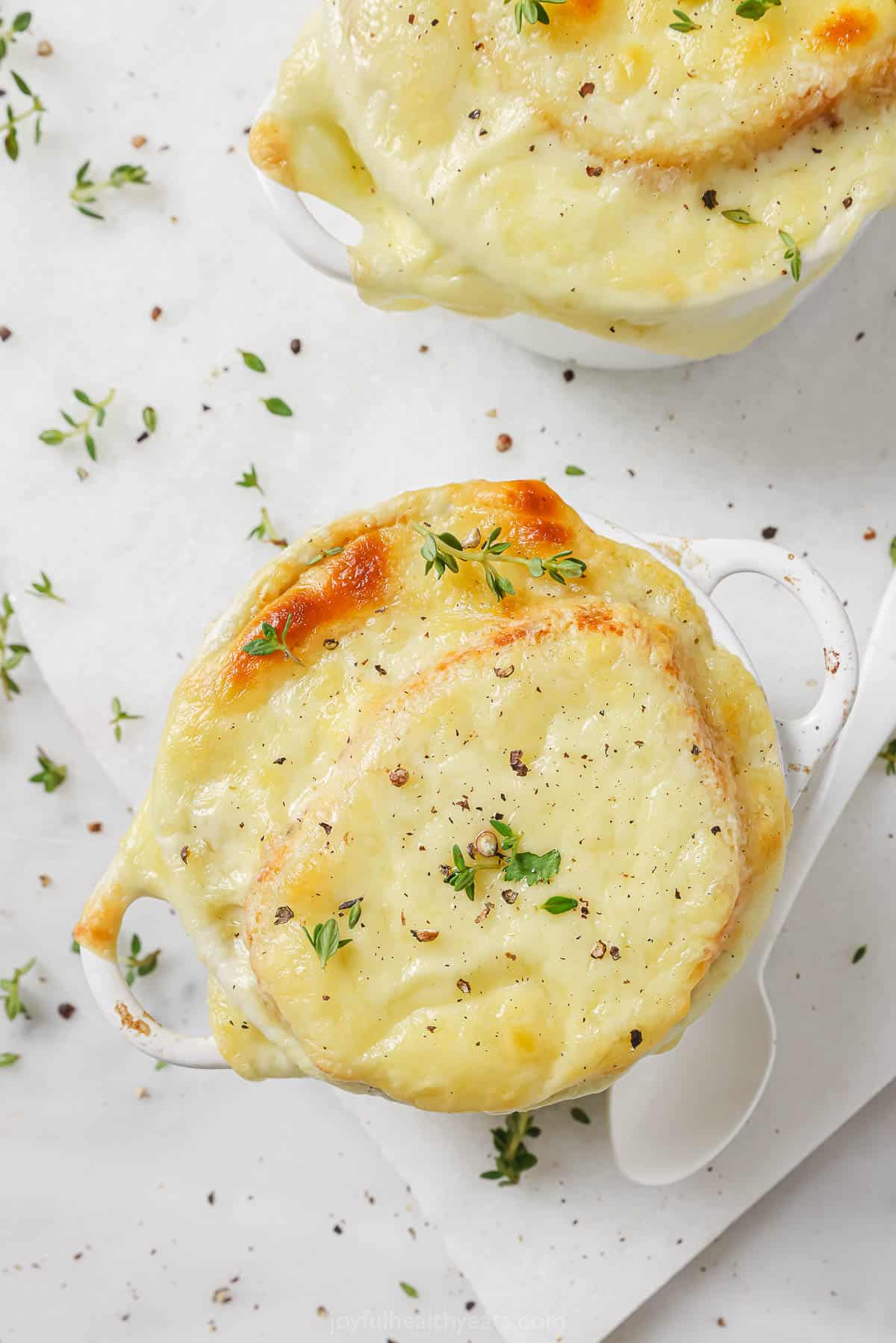 Overhead photo of French onion soup topped wit melty Gruyere. 