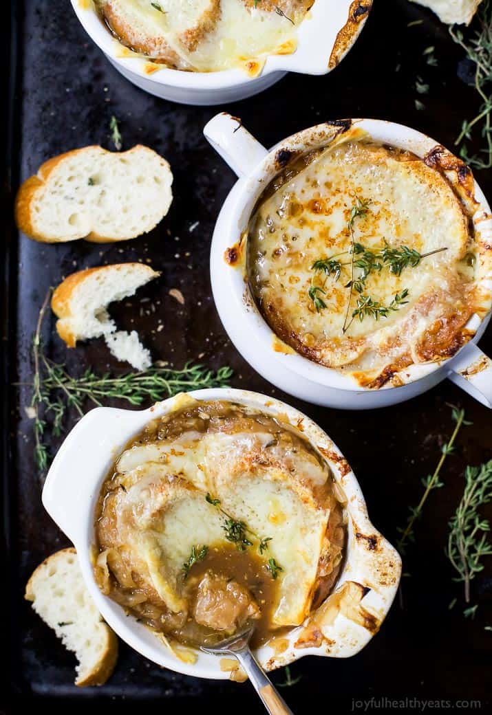 A spoon scooping French Onion Soup out of a white bowl
