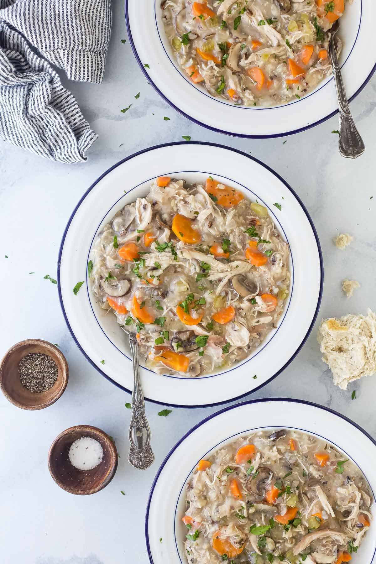 This creamy Crockpot Chicken and Wild Rice Soup is filled with wild rice, tender chicken, and veggies. Only 5 minutes of prep time! chicken and rice soup in a white bowl with a spoon