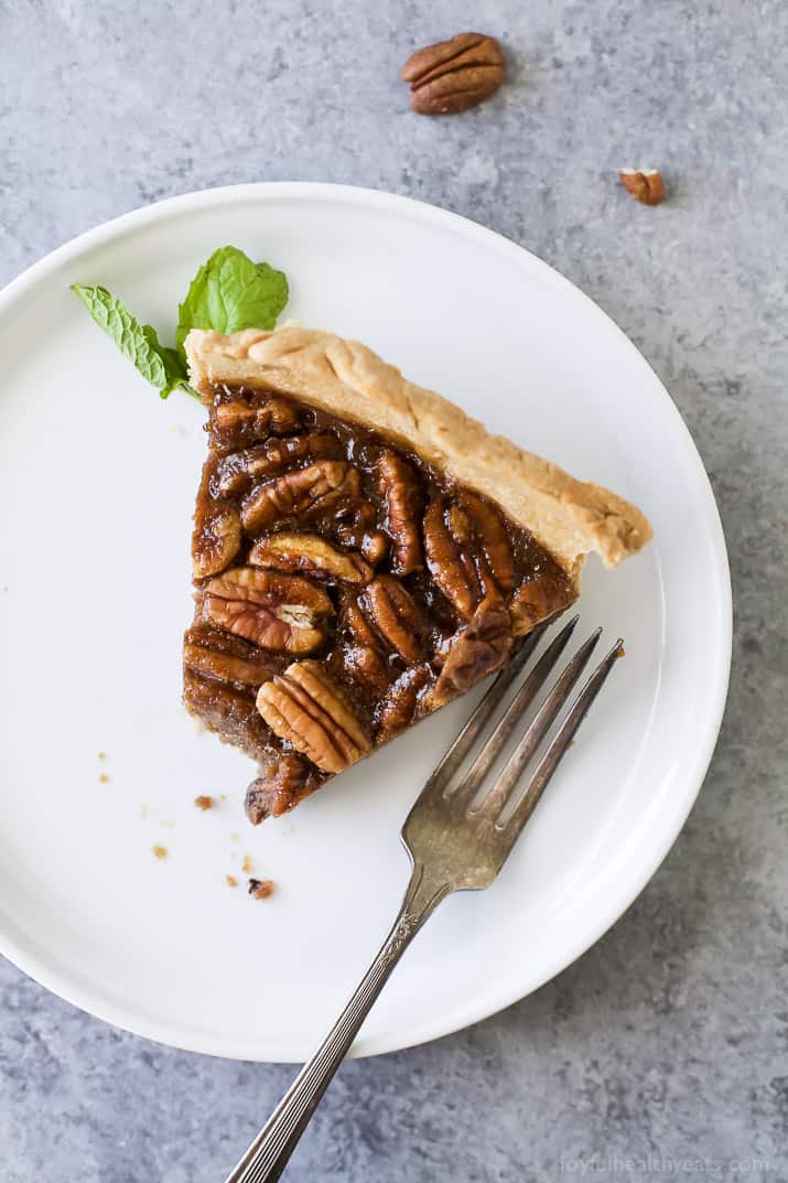 This buttery pecan pie recipe is packed with warm, cozy flavors. It doesn't have any corn syrup to make it the perfect fall treat. Slice of pecan pie recipe on a plate.